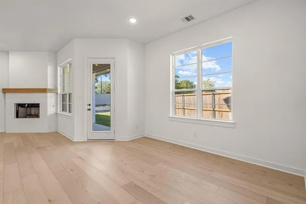 a view of empty room with wooden floor and fireplace