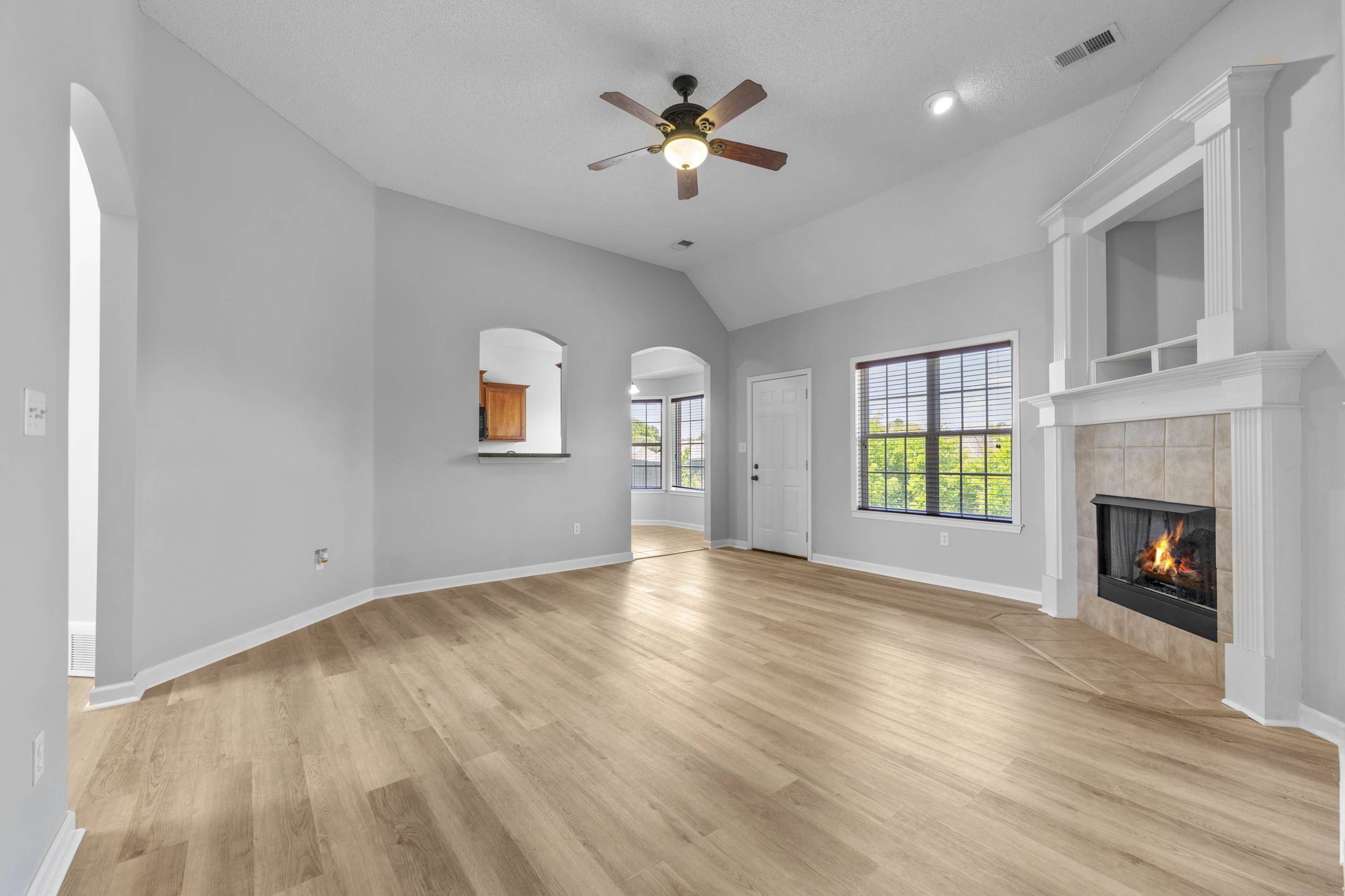 50 Abbey Road Oakland, TN 38060 - Photo 6 of 26 Spacious living area featuring vaulted ceilings, wood-finish flooring, a corner fireplace with a tiled surround, a ceiling fan, and large windows