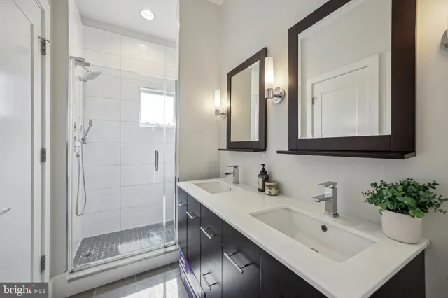 a bathroom with a double vanity sink mirror and shower