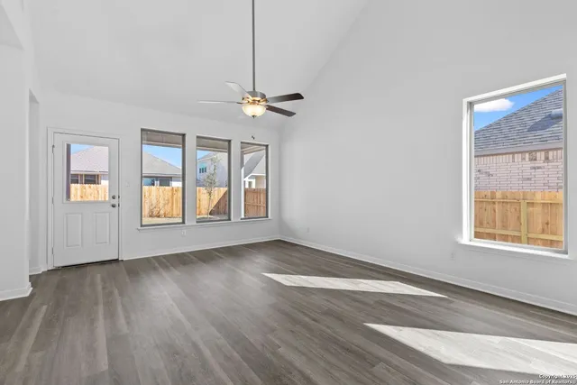 a view of an empty room with a window and wooden floor