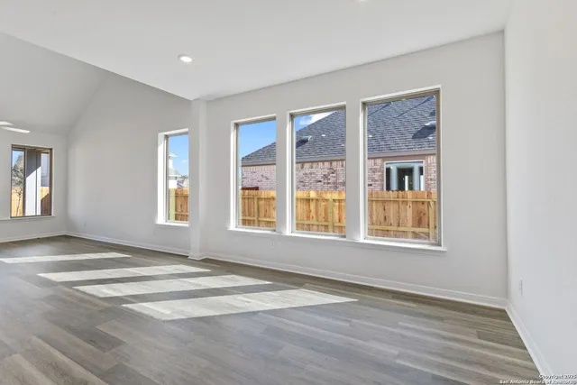 a view of an empty room with a window and wooden floor