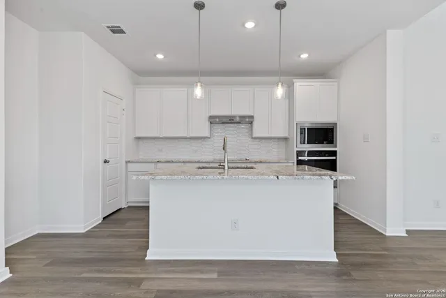 a view of kitchen with stainless steel appliances granite countertop a stove a sink and a refrigerator