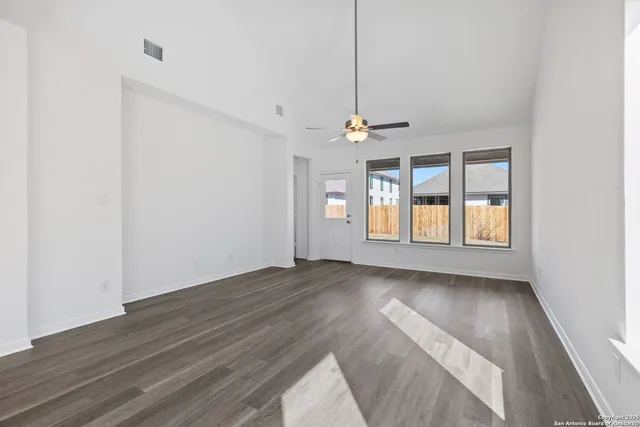 a view of an empty room with window and chandelier fan
