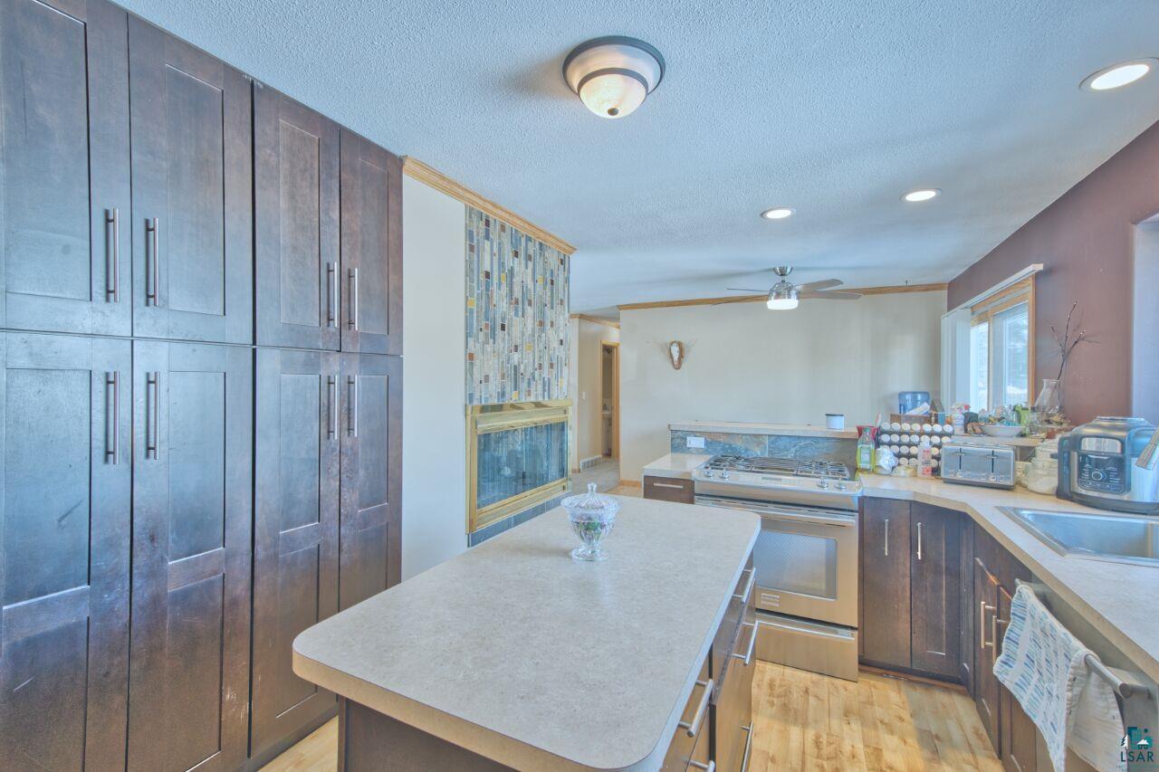 203 Wyandotte Road Hoyt Lakes, MN 55750 - Photo 12 of 39 Kitchen with stainless steel appliances, light countertops, light wood-style floors, a center island, and a textured ceiling