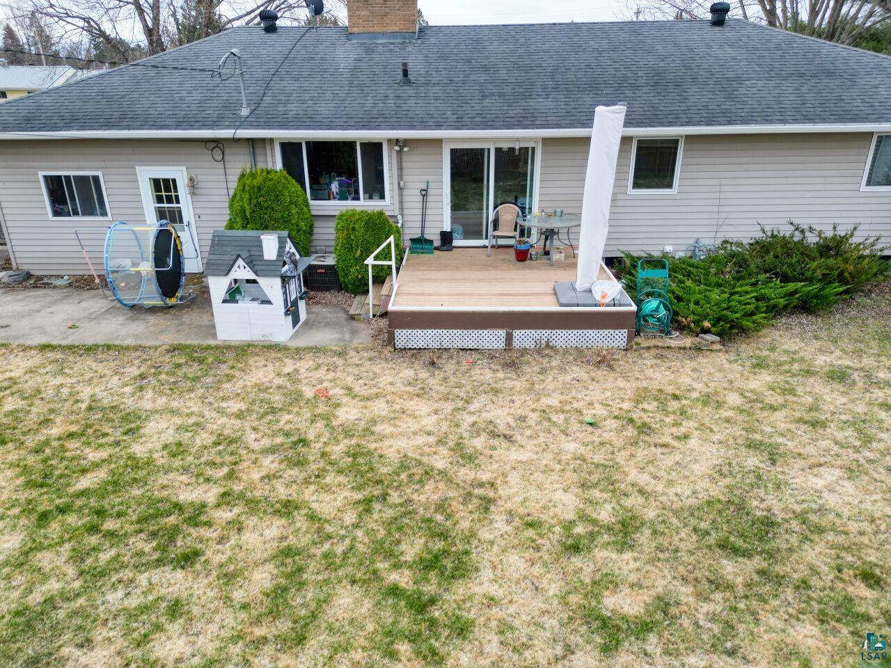 203 Wyandotte Road Hoyt Lakes, MN 55750 - Photo 29 of 39 Rear exterior featuring light-colored siding, a dark shingled roof, and a raised composite deck with white lattice skirting