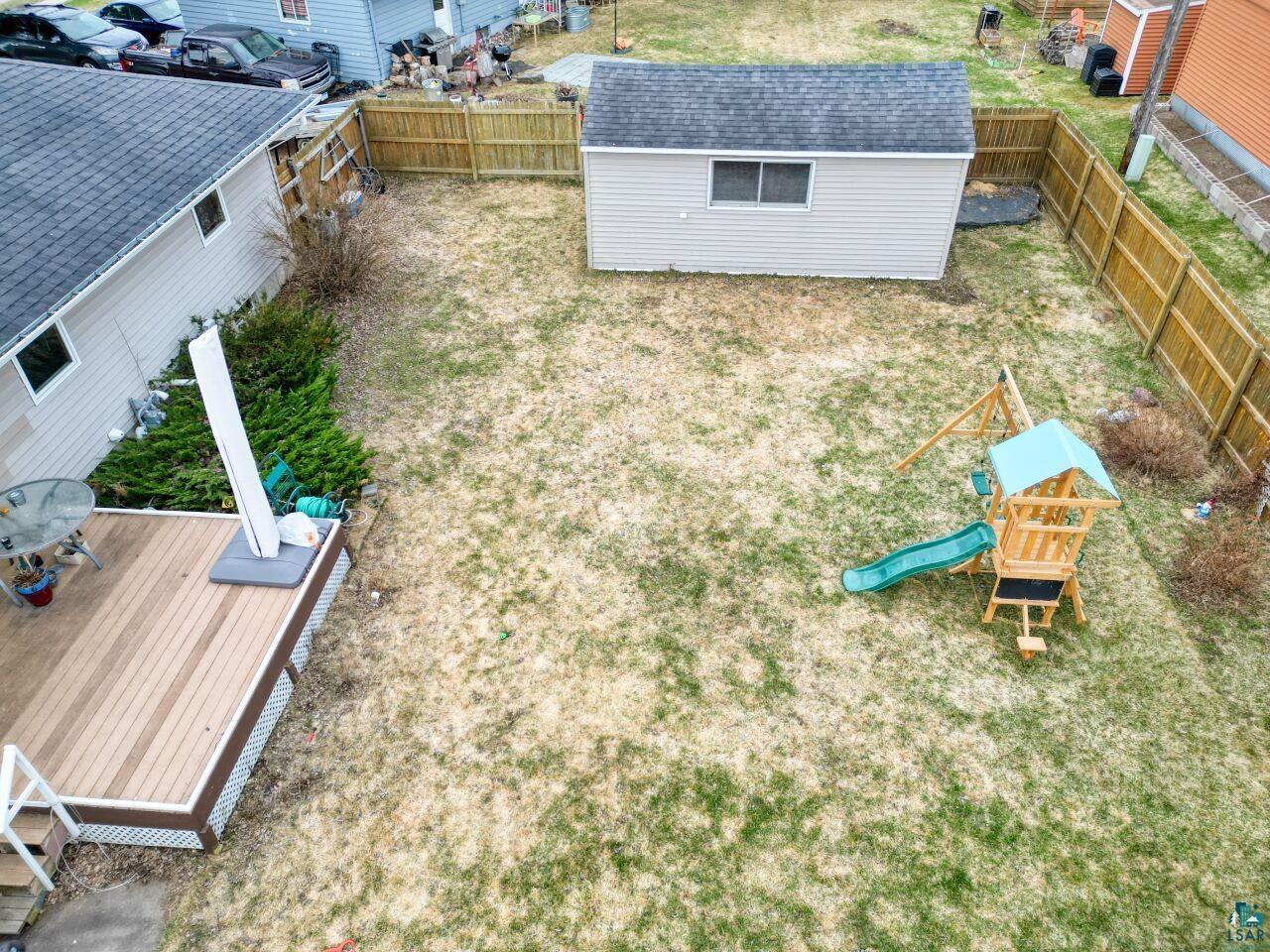 203 Wyandotte Road Hoyt Lakes, MN 55750 - Photo 31 of 39 Expansive backyard featuring a composite deck, a storage shed with shingle roofing, and perimeter wood fencing