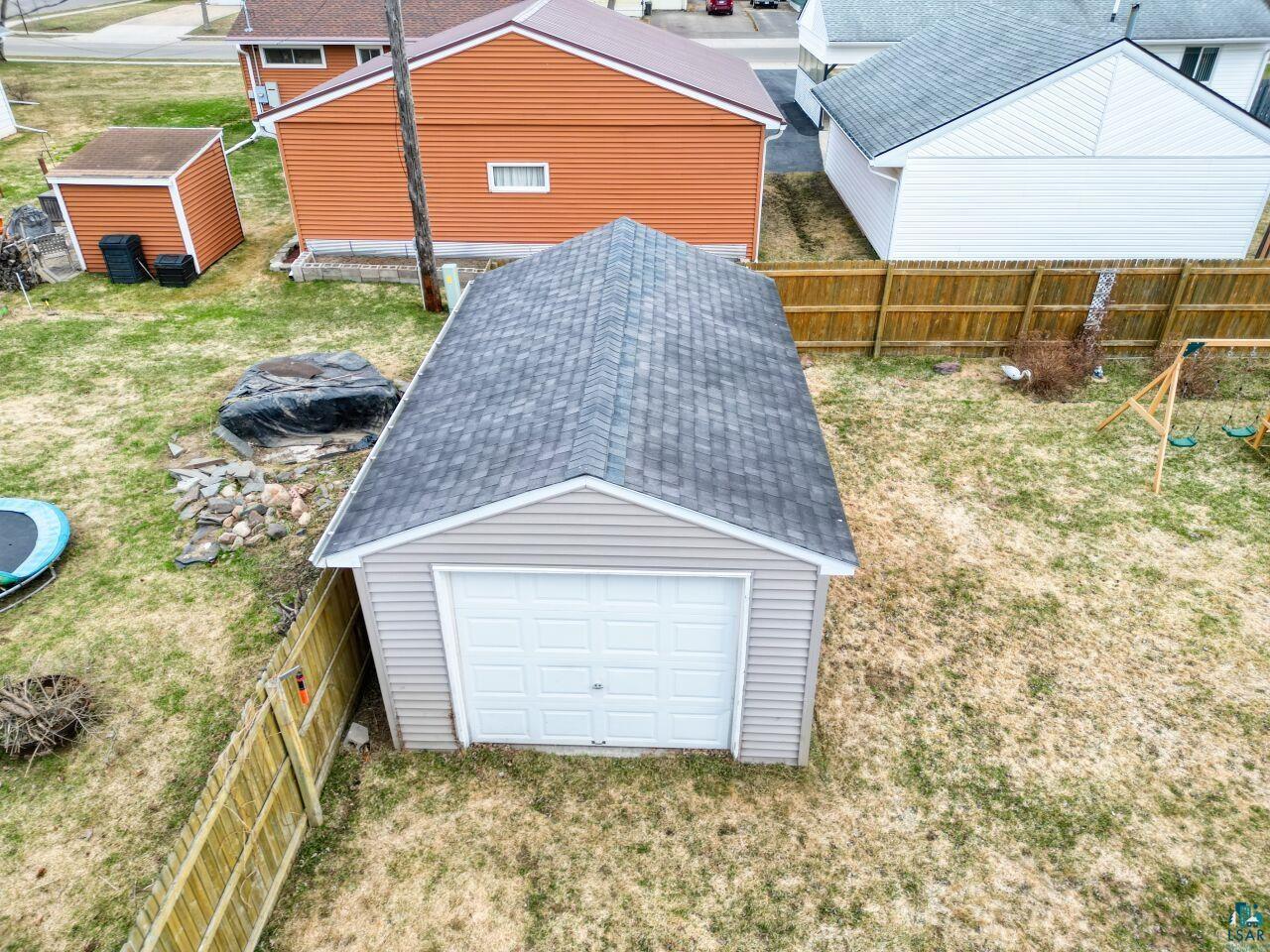 203 Wyandotte Road Hoyt Lakes, MN 55750 - Photo 33 of 39 Detached garage with a gray shingle roof, light-colored siding, and a white panel garage door