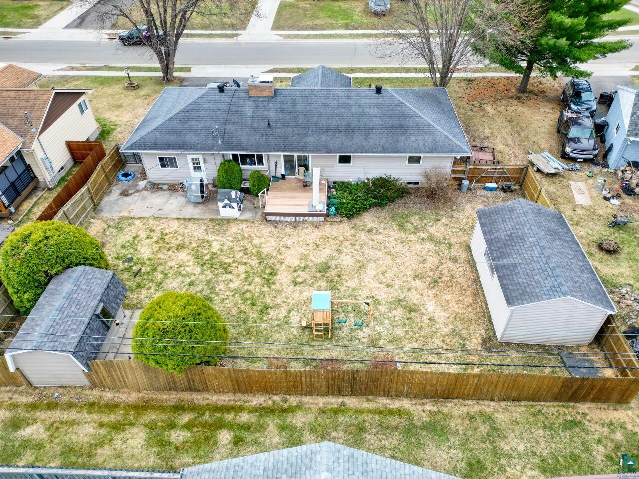203 Wyandotte Road Hoyt Lakes, MN 55750 - Photo 34 of 39 Rear exterior featuring a wood deck, concrete patio, fenced yard, and two detached storage sheds