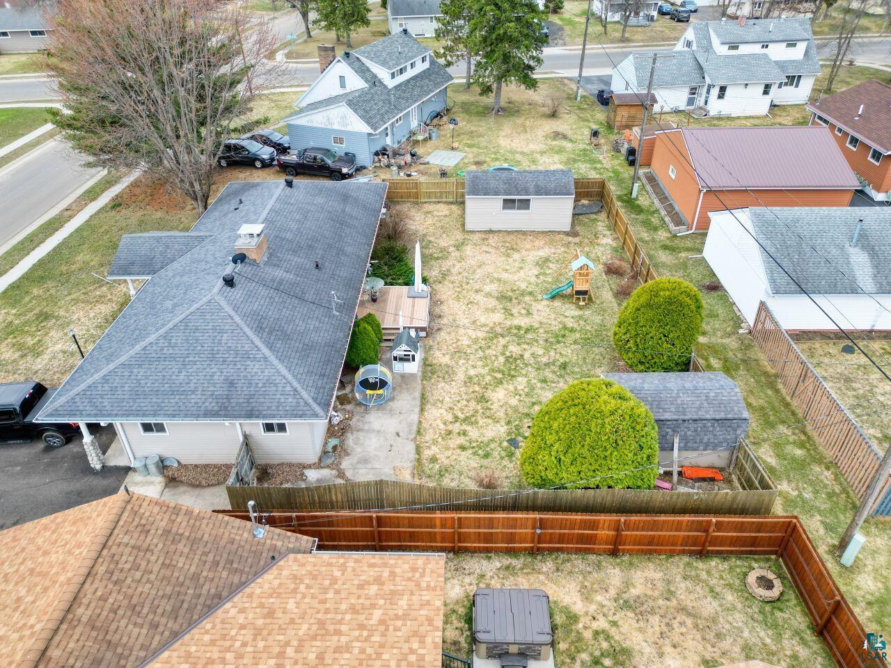 203 Wyandotte Road Hoyt Lakes, MN 55750 - Photo 36 of 39 Expansive rear yard featuring two storage sheds, a wooden privacy fence, and concrete patio space