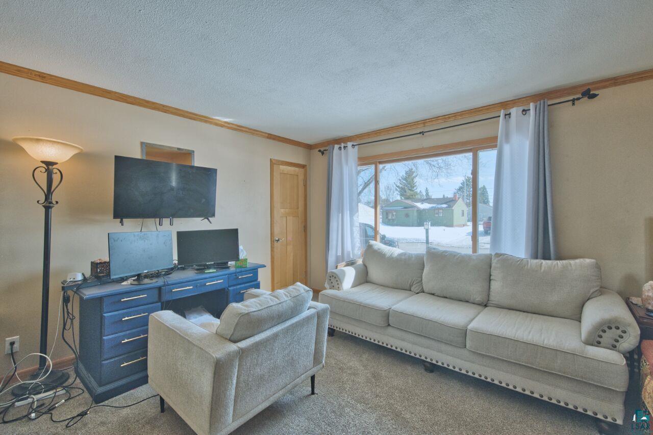 203 Wyandotte Road Hoyt Lakes, MN 55750 - Photo 5 of 44 Carpeted living area with crown molding and a textured ceiling
