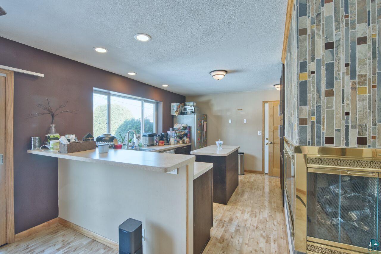 203 Wyandotte Road Hoyt Lakes, MN 55750 - Photo 9 of 44 Kitchen with a peninsula, light countertops, light wood-style flooring, a kitchen island, and a textured ceiling