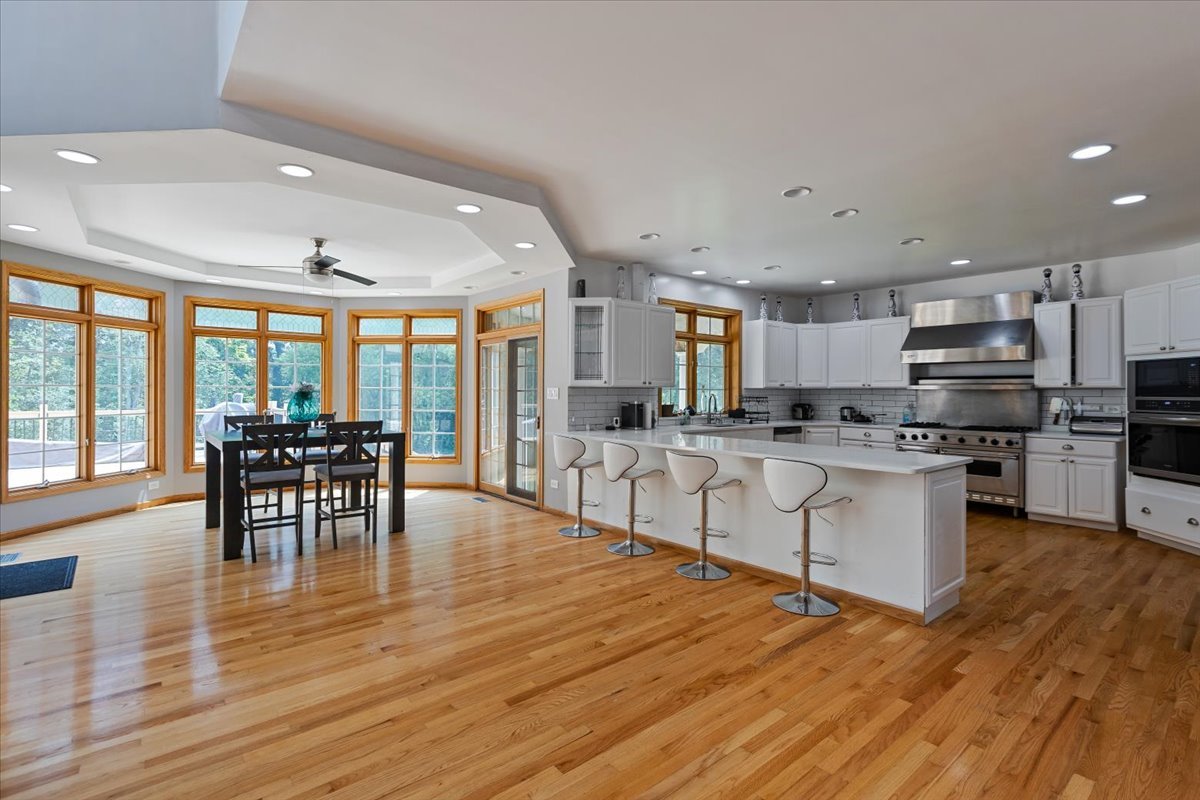 872 Rosedale Terrace Crete, IL 60417 - Photo 18 of 54 a kitchen with stainless steel appliances granite countertop a stove top oven a dining table and chairs with wooden floor