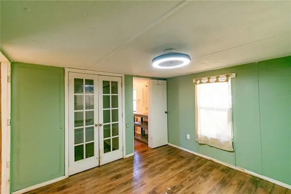 a view of empty room with wooden floor and fan