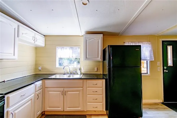 a kitchen with granite countertop white cabinets and refrigerator