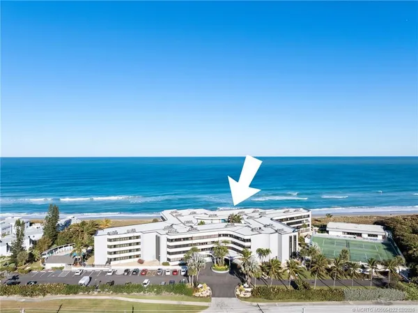 an aerial view of ocean and residential houses with outdoor space