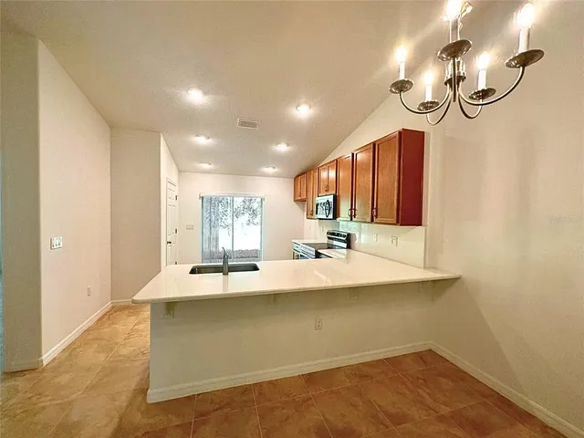 a view of a kitchen counter space a sink wooden floor and a chandelier
