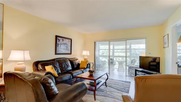a living room with furniture a flat screen tv and a floor to ceiling window