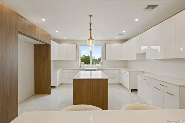 a kitchen with kitchen island a white counter top space cabinets and stainless steel appliances