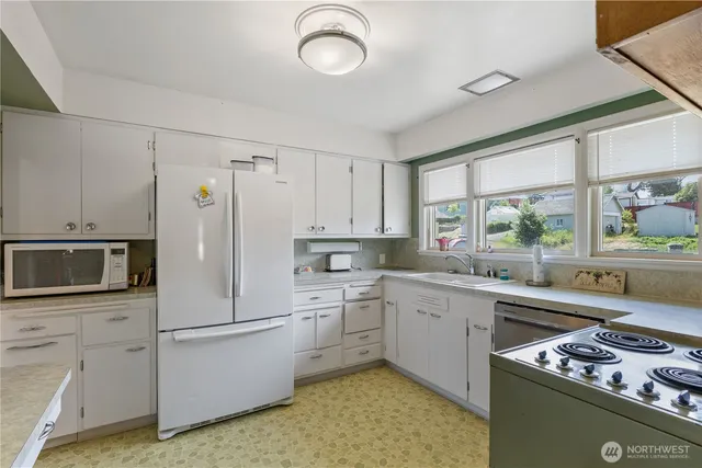 a kitchen with a stove a sink and white cabinets with wooden floor