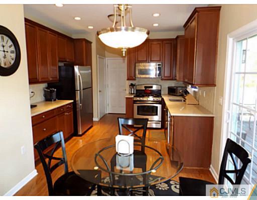 10 Carnation Road Monroe Township, NJ 08831 - Photo 6 of 25 a kitchen with stainless steel appliances granite countertop a stove a refrigerator a sink a dining table and chairs with wooden floor