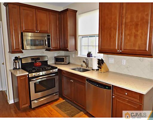10 Carnation Road Monroe Township, NJ 08831 - Photo 8 of 25 a kitchen with wooden cabinets a sink and a stove