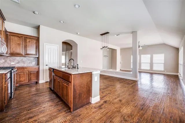 a kitchen with stainless steel appliances granite countertop a sink a stove and wooden floors