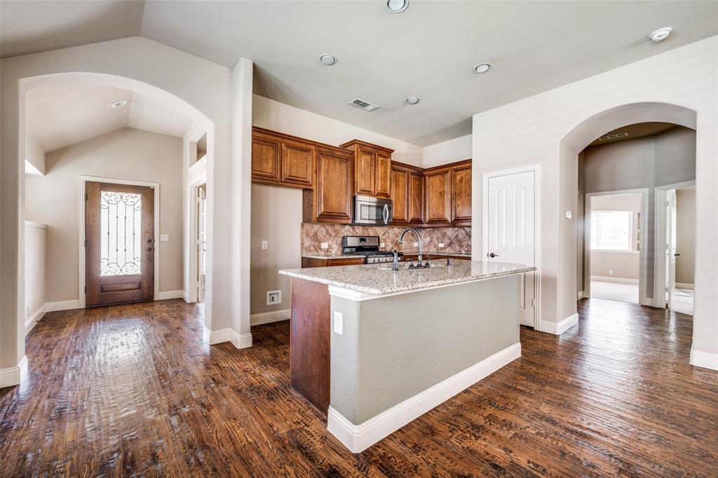 817 Lighthouse Lane Savannah, TX 76227 - Photo 12 of 20 a kitchen with stainless steel appliances granite countertop a refrigerator a stove and a wooden floors
