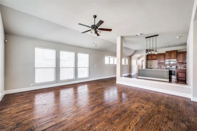 a view of an empty room with a window and wooden floor