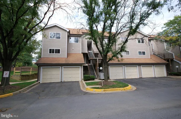 a view of a white house with a large tree and wooden fence