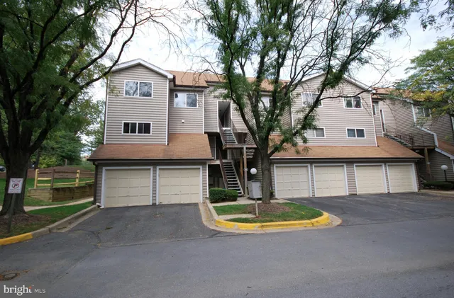 a view of a white house with a large tree and wooden fence