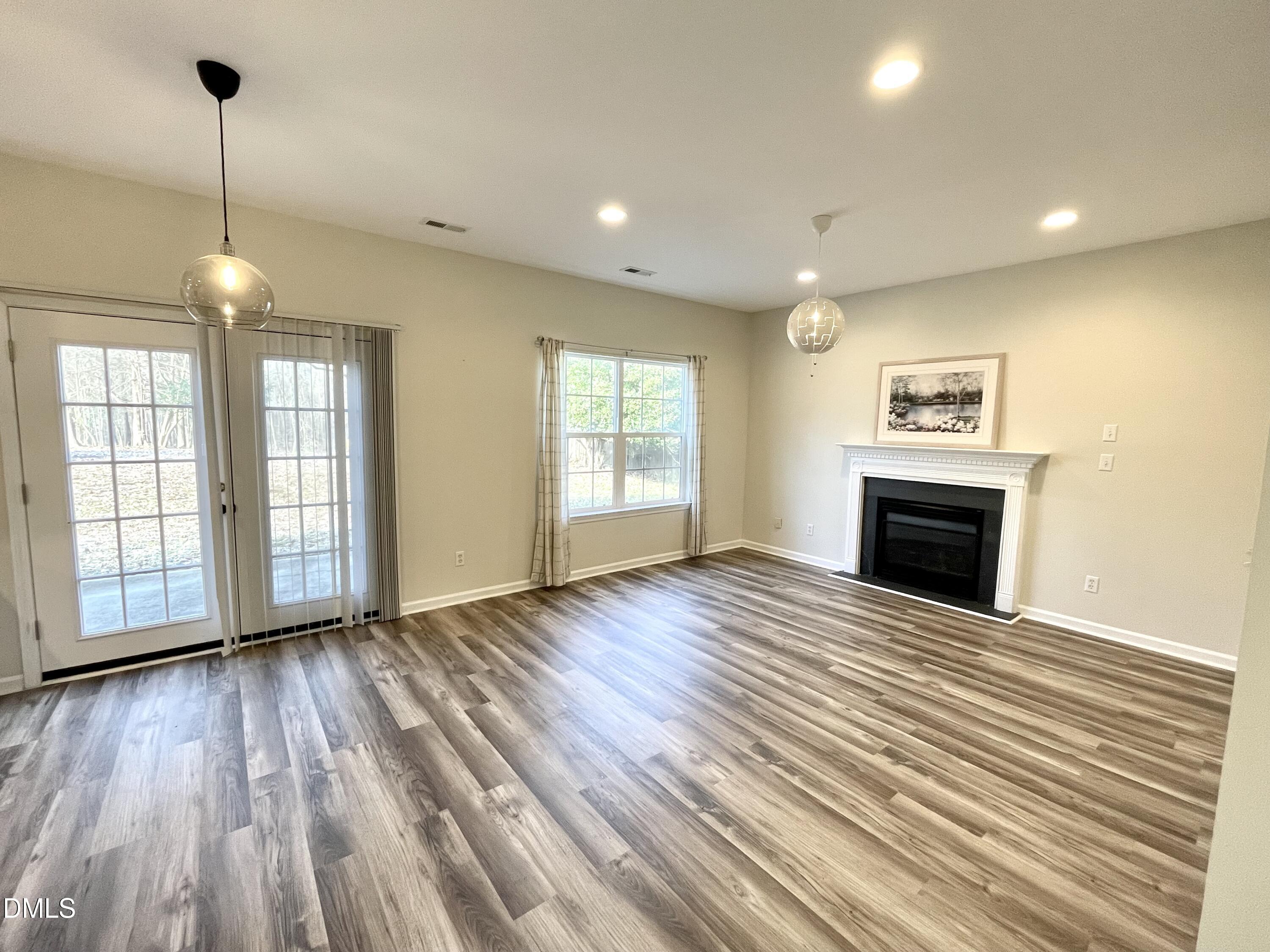 5506 Grand Mesa Drive Durham, NC 27713 - Photo 11 of 28 a view of an empty room with wooden floor fireplace and a window