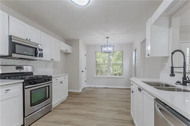 a kitchen with stainless steel appliances granite countertop a sink a stove a microwave and wooden floor