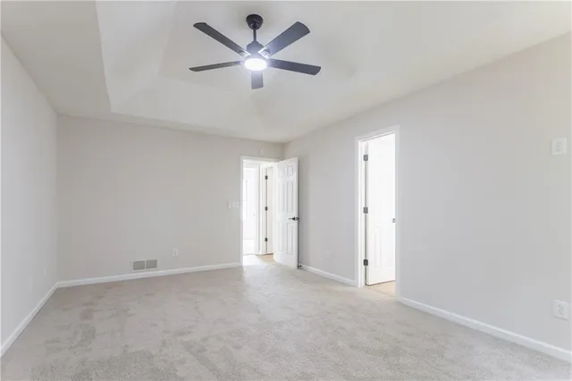an empty room with a chandelier fan and windows