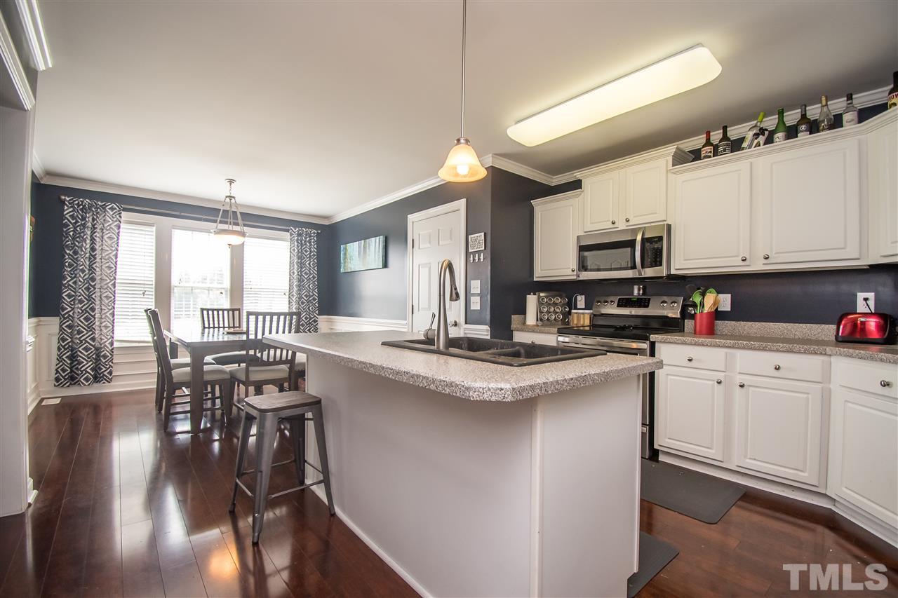 4813 Kure Road Raleigh, NC 27603 - Photo 6 of 25 a kitchen with stainless steel appliances granite countertop a stove top oven a sink dishwasher a dining table and chairs with wooden floor