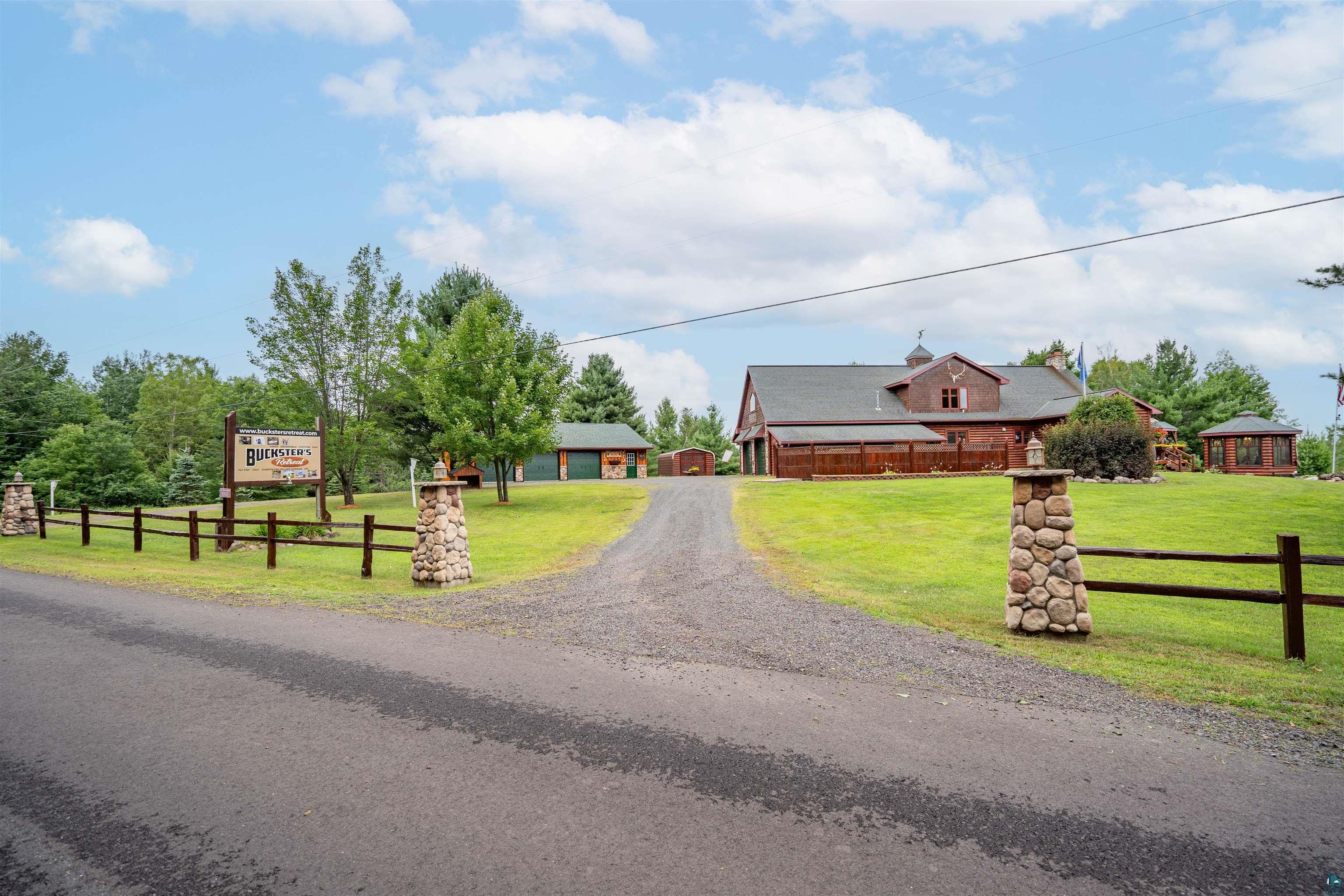 11911 East Rowe Road Lake Nebagamon, WI 54849 - Photo 23 of 61 Gravel driveway entrance featuring stone pillars and a split-rail fence