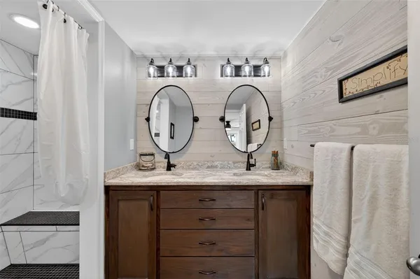 a bathroom with a granite countertop double vanity sink and mirror
