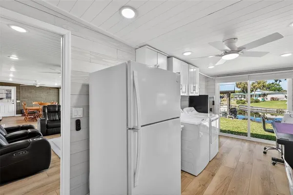 a kitchen with stainless steel appliances a refrigerator a sink dishwasher a stove and a dining table with wooden floor