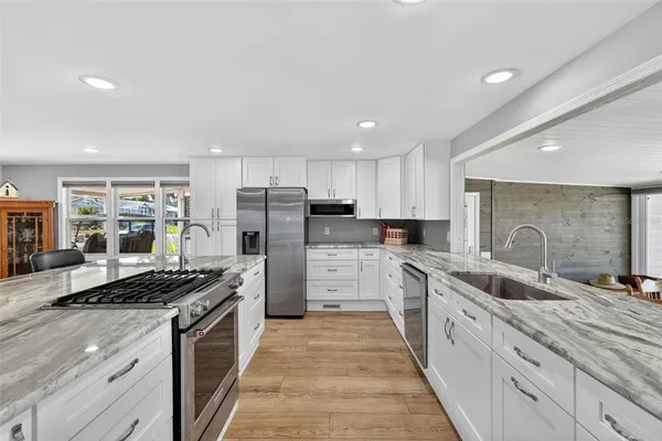 a kitchen with stainless steel appliances kitchen island granite countertop a sink stove refrigerator and cabinets