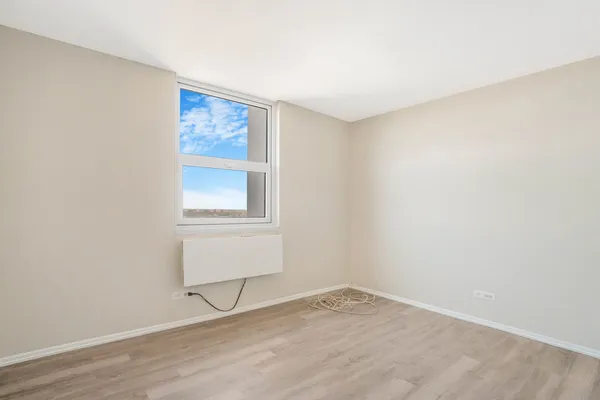 a view of an empty room with wooden floor and a window
