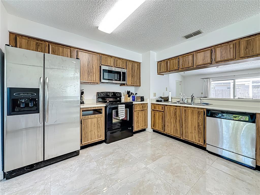 1909 Castle Bay Court Oldsmar, FL 34677 - Photo 5 of 48 a kitchen with stainless steel appliances kitchen island granite countertop a refrigerator a sink a stove top oven a counter space and cabinets
