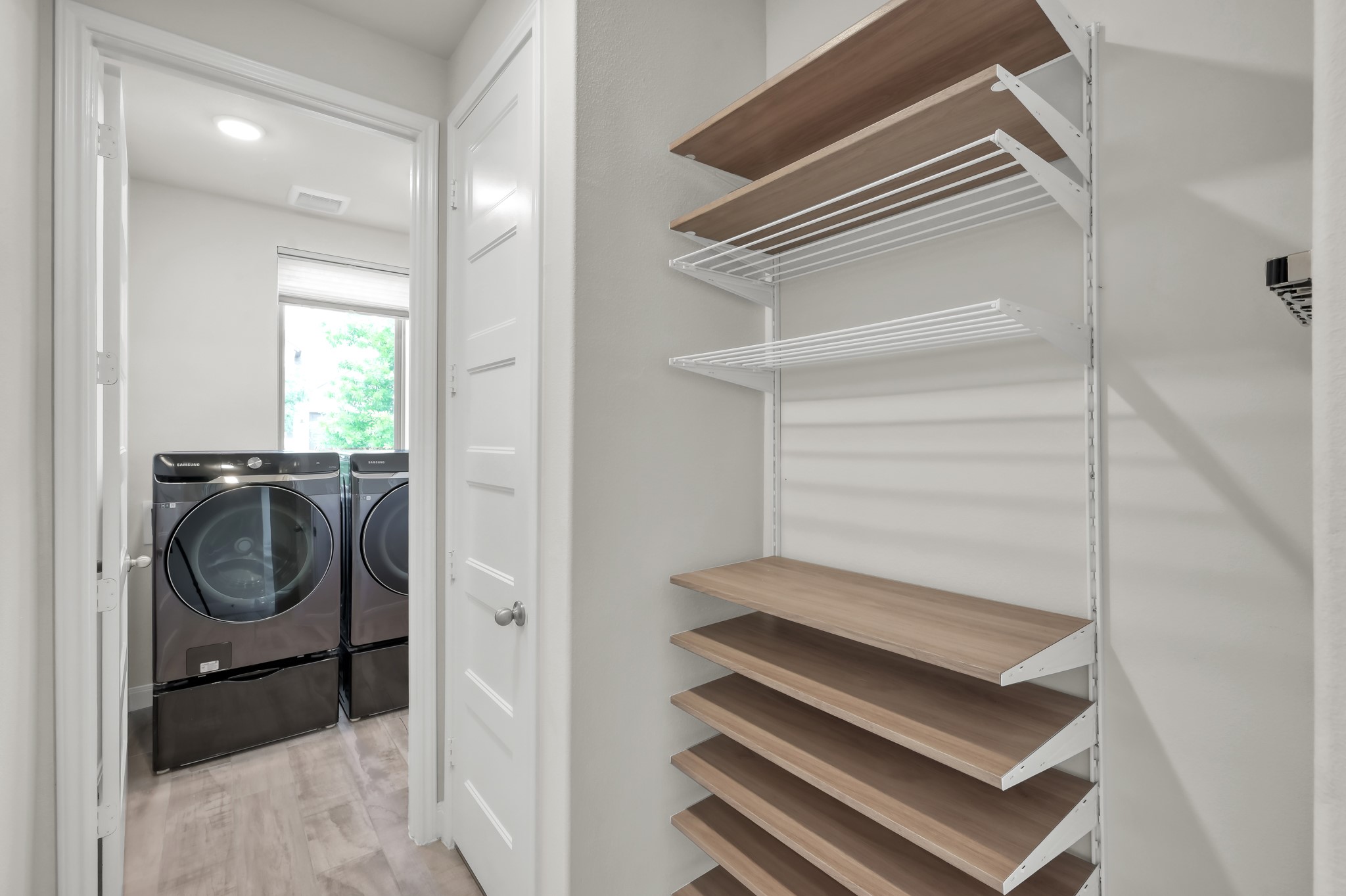 550 Chestnut Reef Court Conroe, TX 77304 - Photo 24 of 46 Clean, modern storage nook with adjustable shelving beside a bright laundry room—simple and functional.