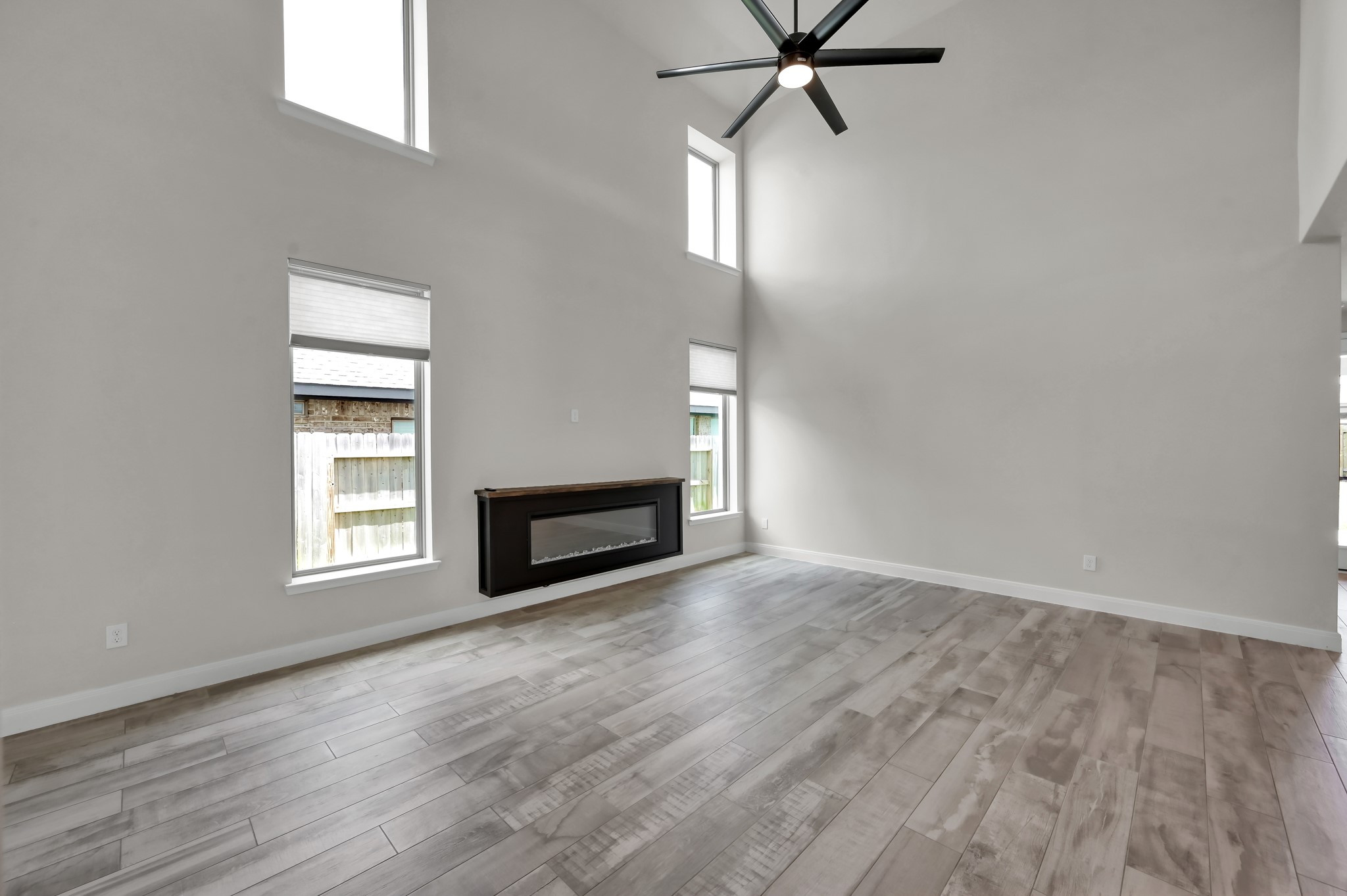 550 Chestnut Reef Court Conroe, TX 77304 - Photo 9 of 46 Light-filled living room with soaring ceilings, tall windows, and a sleek electric fireplace.