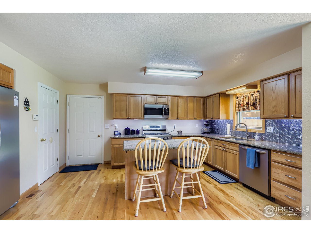 121 Chestnut Street Windsor, CO 80550 - Photo 13 of 42 a kitchen with stainless steel appliances granite countertop a stove top oven a sink dishwasher and white cabinets with wooden floor