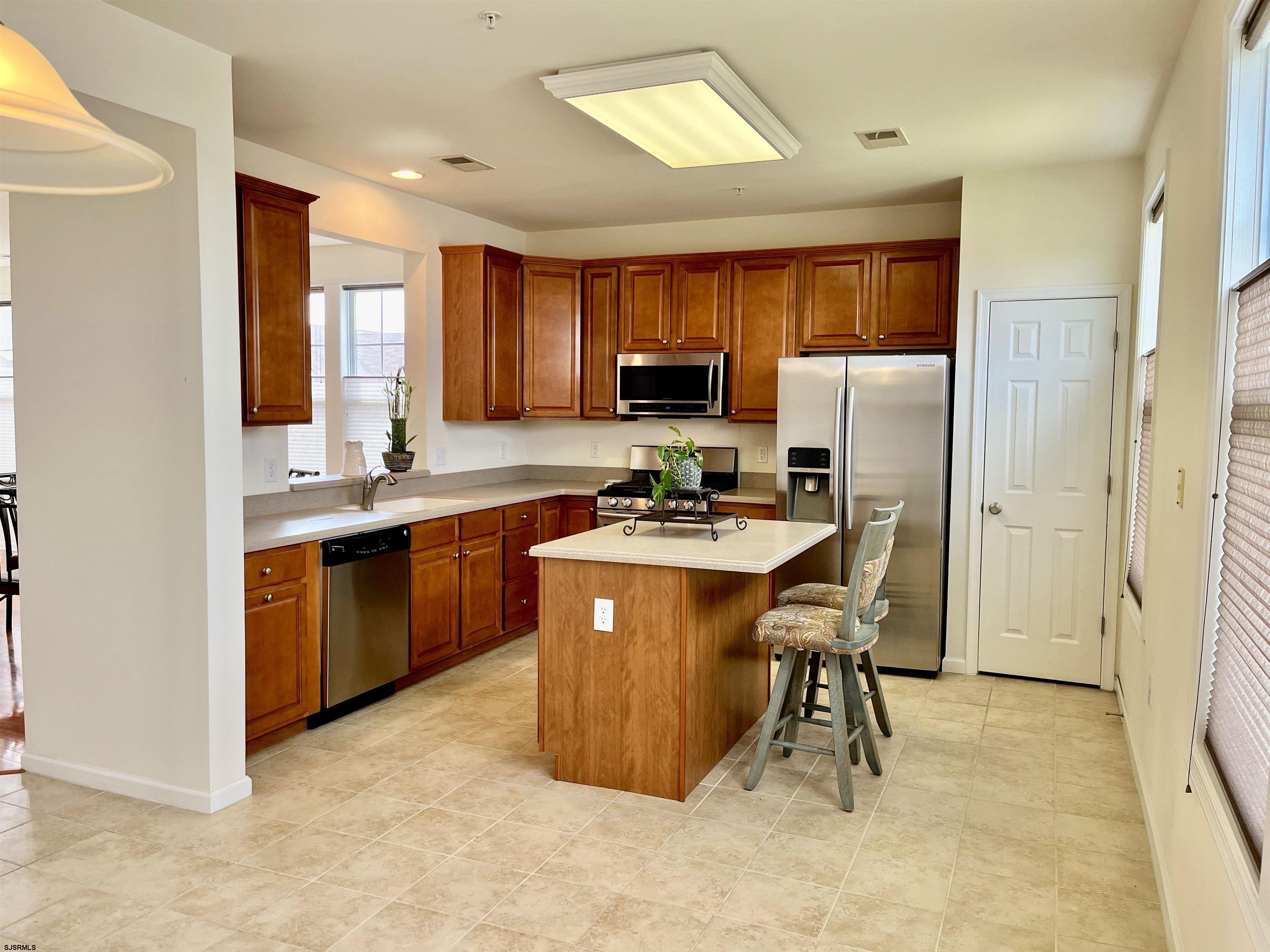 130 Dunlin Lane, Unit 16 Pleasantville, NJ 08232 - Photo 6 of 47 a kitchen with stainless steel appliances a refrigerator a sink a stove a microwave a dining table and chairs