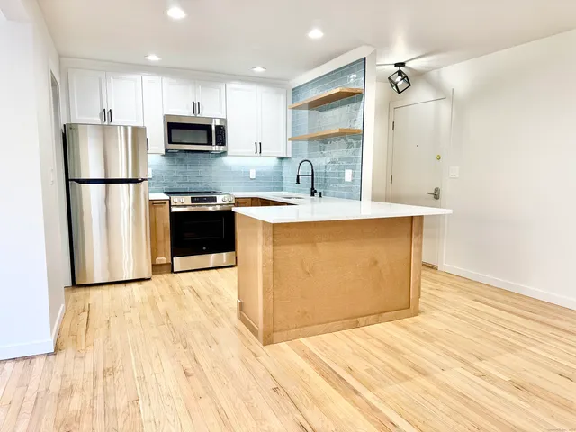 a large kitchen with stainless steel appliances granite countertop a stove a sink and a refrigerator