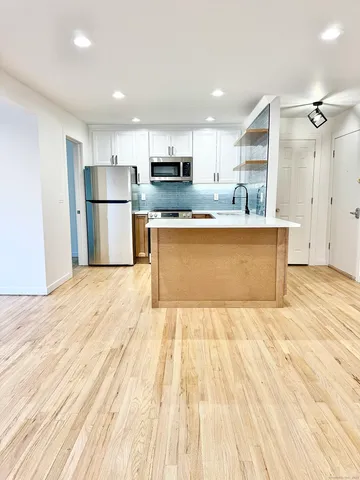 a large kitchen with stainless steel appliances a refrigerator and a stove top oven