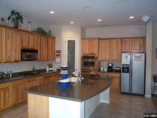 1672 Broadstone Way Reno, NV 89521 - Photo 5 of 8 a kitchen with stainless steel appliances granite countertop a sink refrigerator and microwave