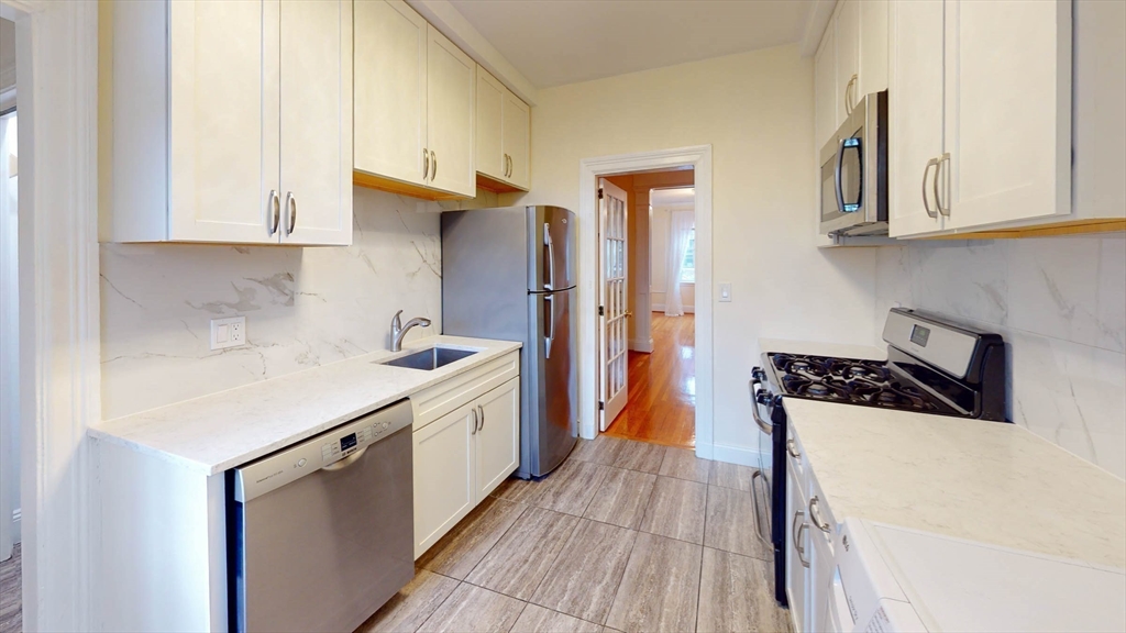 311 Tappan Street, Unit 3 Brookline, MA 02445 - Photo 16 of 35 a kitchen with stainless steel appliances a sink dishwasher stove refrigerator and cabinets with wooden floor