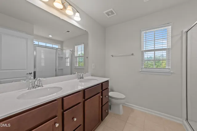 a bathroom with a double vanity sink toilet and a mirror