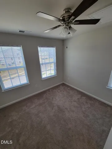 an empty room with windows and fan